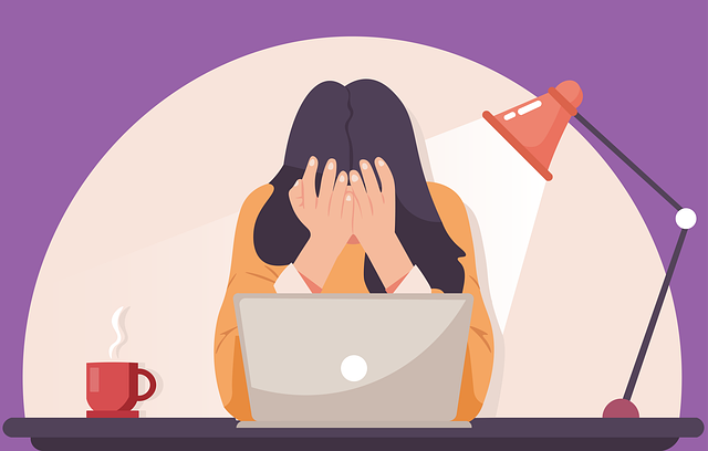 Female student sitting in front of a laptop with her head in her hands