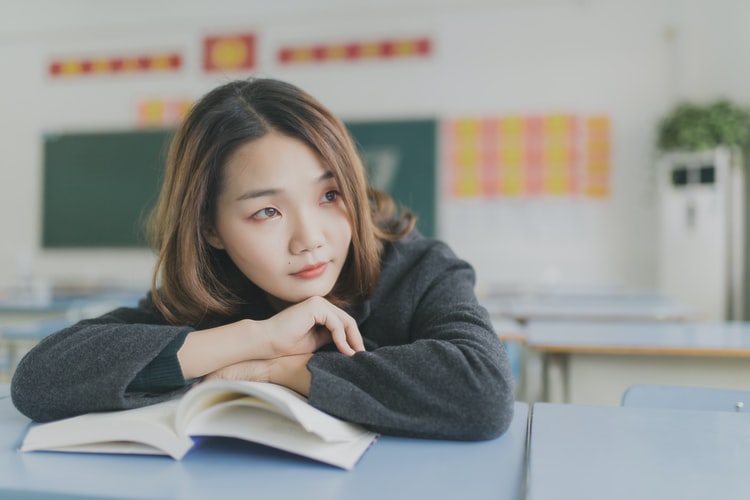 Student in classroom, looking away from book