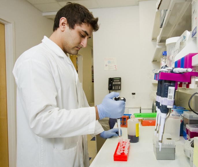male scientist in lab pipetting protein reagent into eppendorf tubes